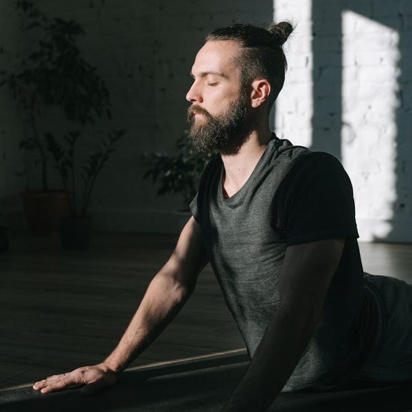 Man meditating peacefully on a yoga mat in a sunlit room.